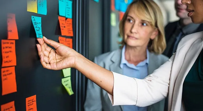 Agile team planning mobile app development tasks with sticky notes on scrum board